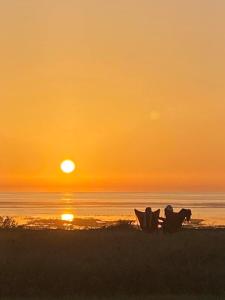a couple of people sitting on the beach at sunset at Le sable chaud in Saint-Pierre-dʼOléron
