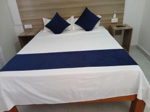 a large bed with blue and white sheets and pillows at Kimbar Suites in Mombasa