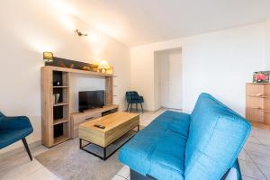 a living room with a blue couch and a tv at 2-3 personnes - Vue Mer et Piscine - Anse à l Âne - trois Îlets - Plage 2 min en voiture in Les Trois-Îlets