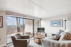 a living room with a couch and chairs and a large window at Notchbrook 5 Apt. in Stowe