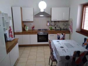 a kitchen with white cabinets and a table with a tablecloth at House " Bond " in Tisno