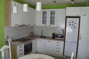 a kitchen with white cabinets and a white refrigerator at Prestige in Šabac