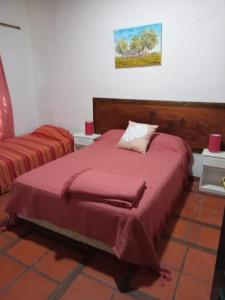 a bedroom with a bed with a red blanket at Hospedaje El Rincon in San Antonio de Areco