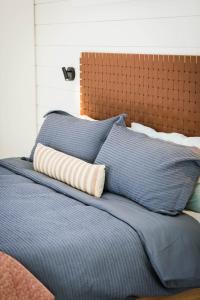 a bed with blue pillows and a brown head board at A-Frame Cliffside Studio Cabins in South Fork