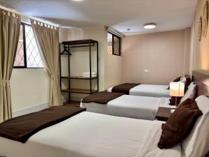 a hotel room with three beds and a window at El Patio Hostel Quito in Quito