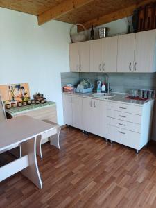 a kitchen with white cabinets and a wooden floor at Arca lui Roman in Furceni +22 photos