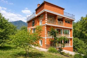 a large orange building with balconies and trees at Chateau Chao in Khulo