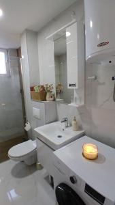 a bathroom with a toilet and a sink with a candle at Koviljača apartman Demetrios in Banja Koviljača +30 photos