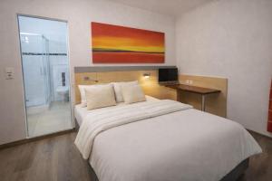 a bedroom with a large white bed and a bathroom at Hotel Moji 5 Solingen in Solingen