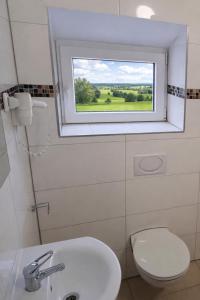 a bathroom with a white toilet and a window at Hotel Moji 5 Solingen in Solingen