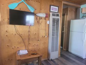 a room with a wall with a television and a table at Outpost Motel on the River in Dolores