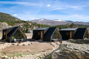 a row of black cabins with mountains in the background at A-Frame Cliffside Studio Cabins in South Fork