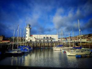 a group of boats docked in a harbor with a lighthouse at Haddock Hideaway at The Whiteley in Scarborough
