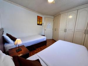 a hotel room with two beds and a table with a lamp at El Patio Hostel Quito in Quito