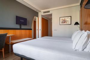 a bedroom with a large white bed and a desk at Dorma Juan de Austria in Valladolid