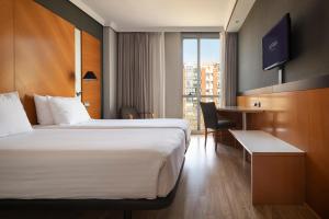 a hotel room with a large bed and a desk at Dorma Juan de Austria in Valladolid