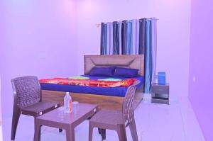 a bedroom with a bed and two chairs and a table at Abhishek chand kaushik guest House in Ayodhya