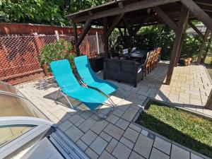 two blue chairs on a patio with a grill at Kovács Apartmanház in Balatonfüred