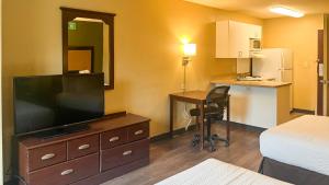 a hotel room with a television on a dresser with a desk at Studio 6 Chantilly VA Washington Dulles Airport in Chantilly