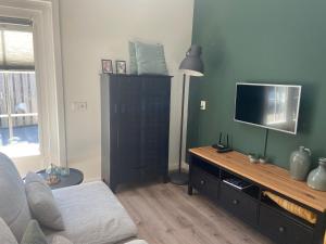 a living room with a flat screen tv on a dresser at Zon en Zee 2 personen in Westkapelle