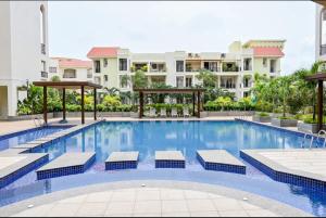 a large swimming pool with loungers in front of a building at Casa Lobo in Mapusa