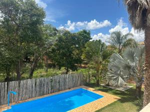 a swimming pool in a yard with a fence and trees at Pousada Brisas da Serra in Serra do Cipo