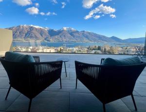 a patio with two chairs and a view of the mountains at Luxury Lake View Apartment Minusio by HolAp in Minusio