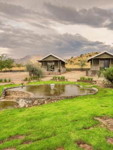 a house with a pond in the middle of a yard at Carlo's Mountain Lodge in Usakos