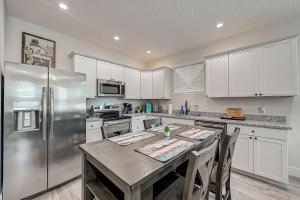 a kitchen with a table and a stainless steel refrigerator at 1mi to Downtown! 3BR6BedsScreenroom,Deck,Firepit in St. Augustine