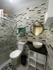 a bathroom with a toilet and a sink and a mirror at Pousada Casamar in Maceió