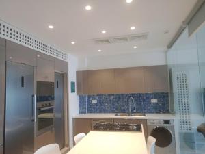 a kitchen with blue tiles on the wall and a sink at L'appartement en face de la baie in Sidi MʼHamed