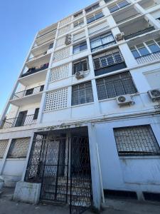 a white building with a gate in front of it at L'appartement en face de la baie in Sidi MʼHamed
