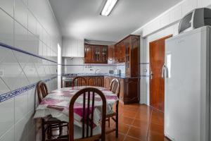 a kitchen with a table and chairs and a refrigerator at Casa do Centro in Peniche
