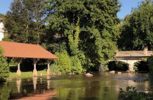 a bridge and a river with a bridge and trees at Friendly Camping and Lodges in Saint-Pardoux-la-Rivière