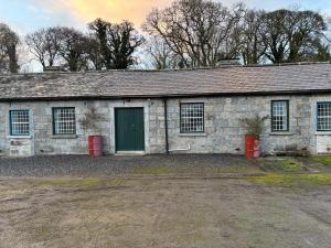 an old stone building with a green door at Carpenters Cottage in Rathvilly