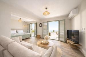 a living room with a couch and a tv and a bed at Hellosummer Boutique suites,near fiscardo! in Andipáta Erísou