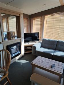 a living room with a couch and a tv at Cozy corner house, New vennepark in De Haan
