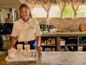 a woman standing behind a counter with two glasses of coffee at Carlo's Mountain Lodge in Usakos +238 photos