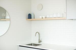 a white kitchen with a sink and a mirror at The Sea Breeze in Timaru +42 photos