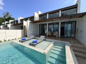 a house with a swimming pool in front of a house at Pano Samui Beachfront Villas in Nathon Bay
