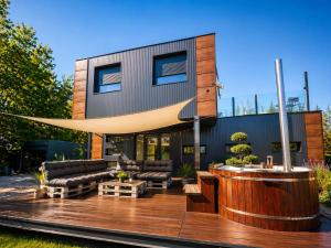 a house with a wooden deck with furniture on it at Swan Apartman in Sándorfalva