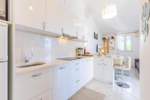 a white kitchen with white cabinets and a sink at Lumbarda Resort Apartments in Lumbarda
