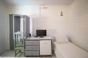 a bedroom with a bed and a desk with a computer at Pousada da Carmô in Fernando de Noronha