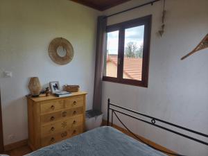a bedroom with a bed and a window and a dresser at Le chalet de Maryvonne in Gibles
