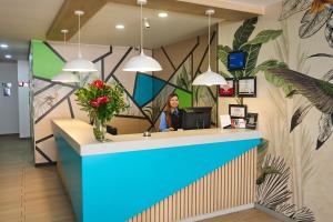a woman sitting at a counter in a lobby with flowers at Hotel Vivre in Medellín