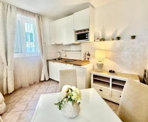 a kitchen with white cabinets and a table with flowers on it at Guesthouse Villa Vice in Split