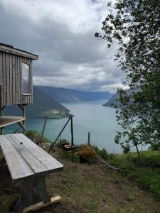 a wooden bench sitting on the side of a lake at Raaum Gard, hytte 3 in Luster