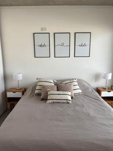 a bedroom with a large bed with four pictures on the wall at Altamar a metros del Hospital Regional y Cabin in Comodoro Rivadavia