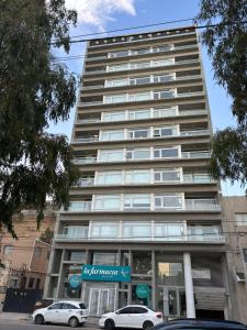 a tall building with cars parked in front of it at Altamar a metros del Hospital Regional y Cabin in Comodoro Rivadavia