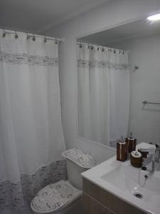 Baño blanco con aseo y lavamanos en Departamento 193, en Coquimbo
